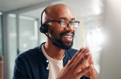 A man wearing a phone headset talking on the phone and smiling