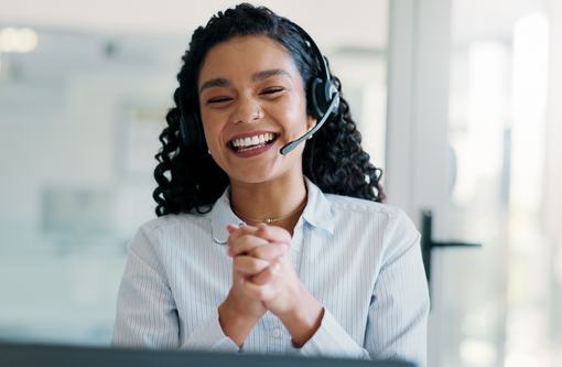 A customer service representative smiling and wearing a phone headset